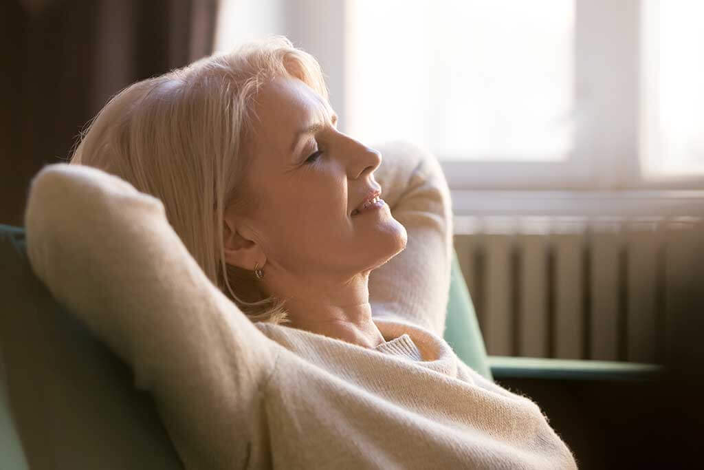 old woman relaxing meditating leaning on comfortable sofa