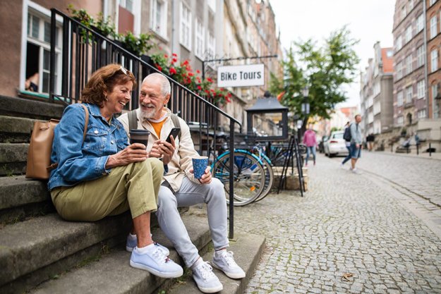 Happy senior couple tourists sitting on stairs