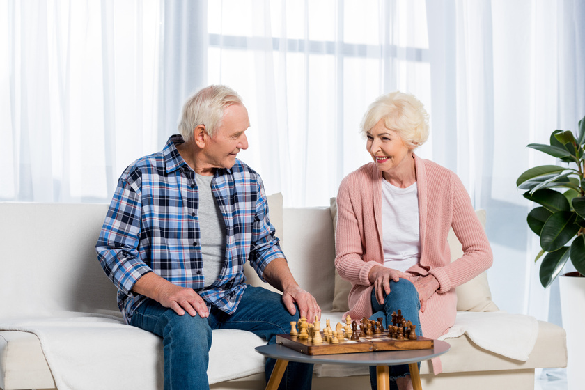 senior couple playing chess at home while sitting on couch The Value Of Independent Living Apartments In Columbus, IN
