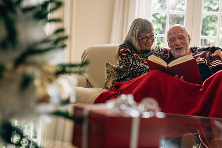 Happy senior couple reading a book sitting at home Enjoying The Holiday Celebrations The Old-Fashioned Way In Independent Living In Columbus, IN