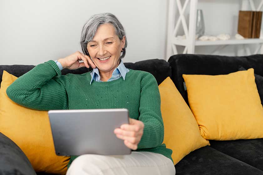 Senior lady is watching series in the touchpad