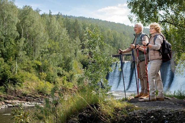 Two happy mature backpackers in activewear standing