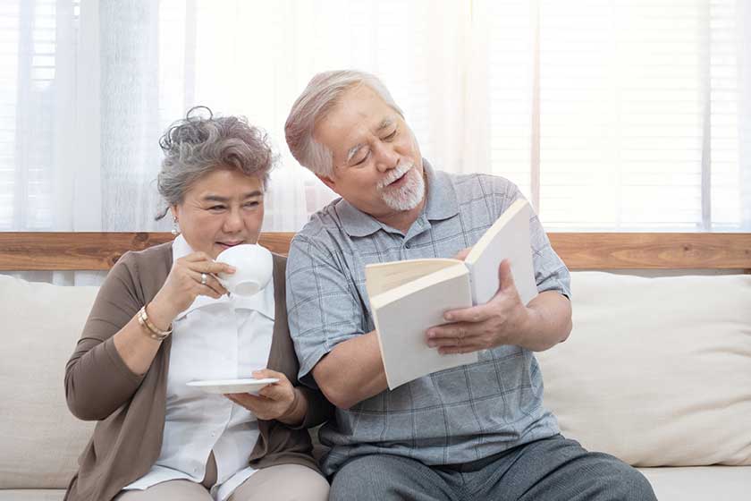 Elderly senior asian couple sitting on sofa reading book together at home.Retirement grandmother and grandfather spend time together at house. Elderly senior asian couple sitting on sofa reading book together at home.Retirement grandmother and grandfather spend time together at house.
