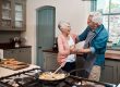 We know how to keep our love going strong. a senior couple dancing while cooking in the kitchen at home