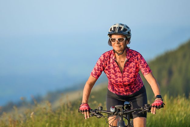 Portrait of pretty senior woman riding her electric mountain bike on the mountains above Oberstaufen , Allgau Alps, Bavaria Germany