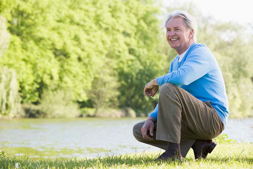 Man outdoors at park by lake smiling