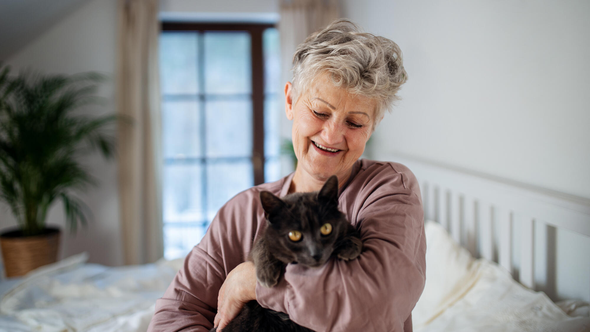 Happy,Senior,Woman,With,Cat,Resting,In,Bed,At,Home.