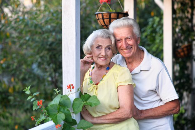 Portrait of beautiful senior couple by lilacs in the park