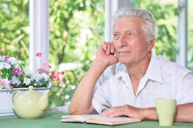 Portrait of senior man reading book with tea