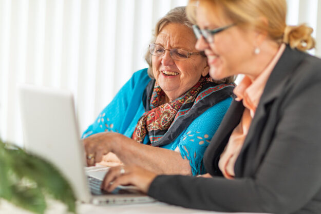 Woman Helping Senior Adult Lady on Laptop Computer.