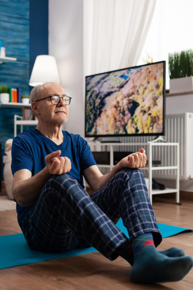 Peaceful senior man practicing meditation workout sitting comfortable in lotus position